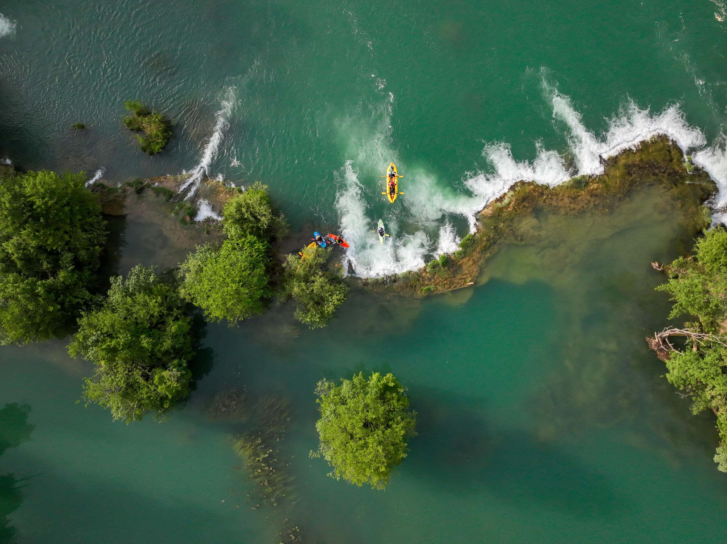 Kayaking guide navigates a waterfall.