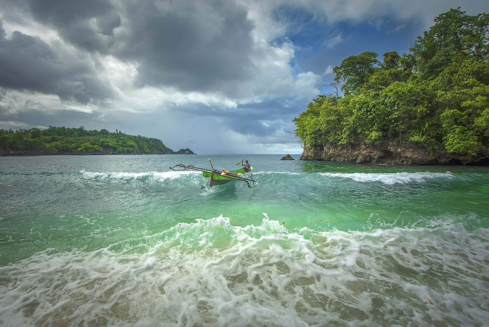 Catamaran navigating surf in tropical bay