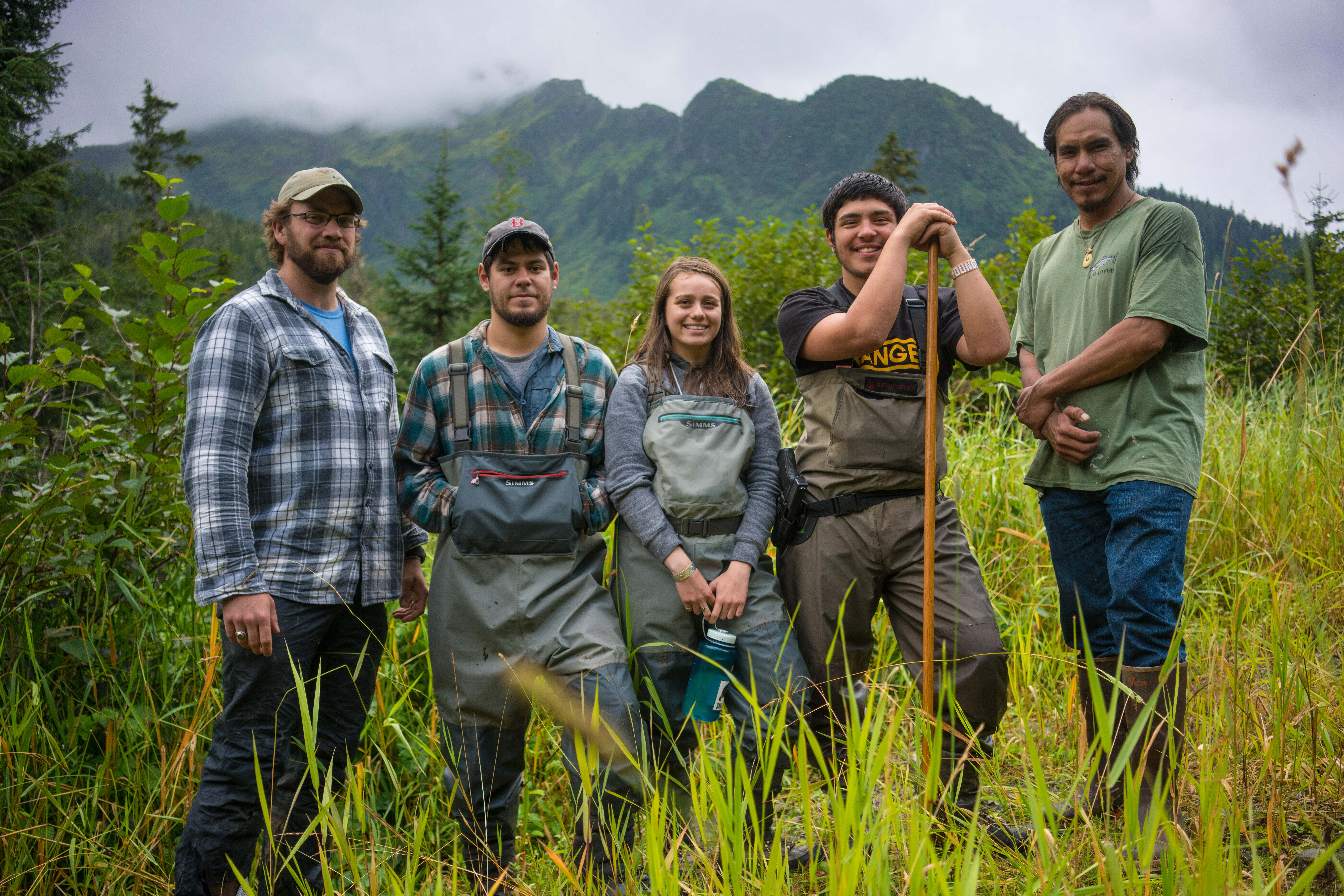 Five people pose for a photo in tall grass.