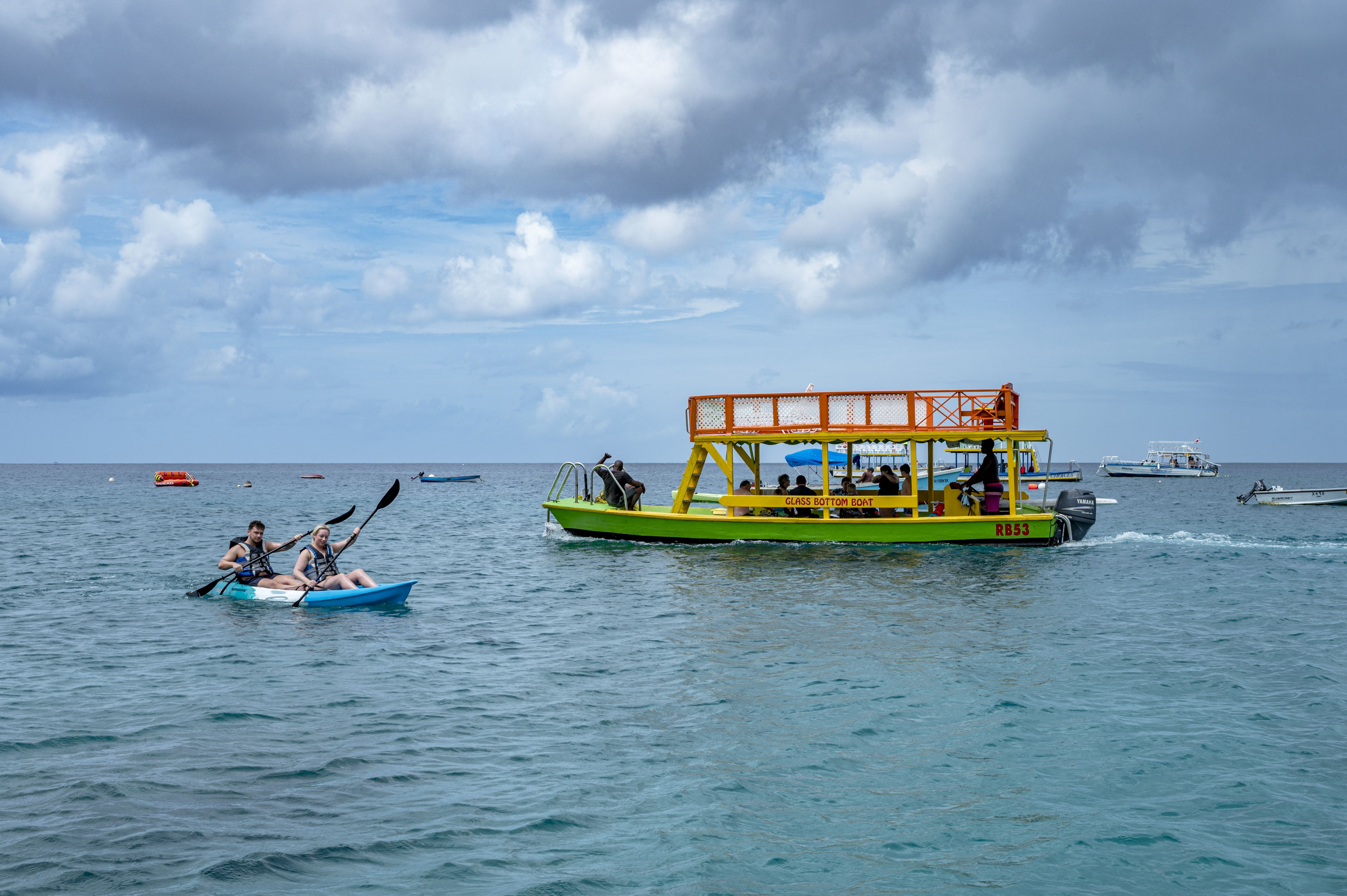 A recreation boat out on the Caribbean sea with people out enjoying water sports.
