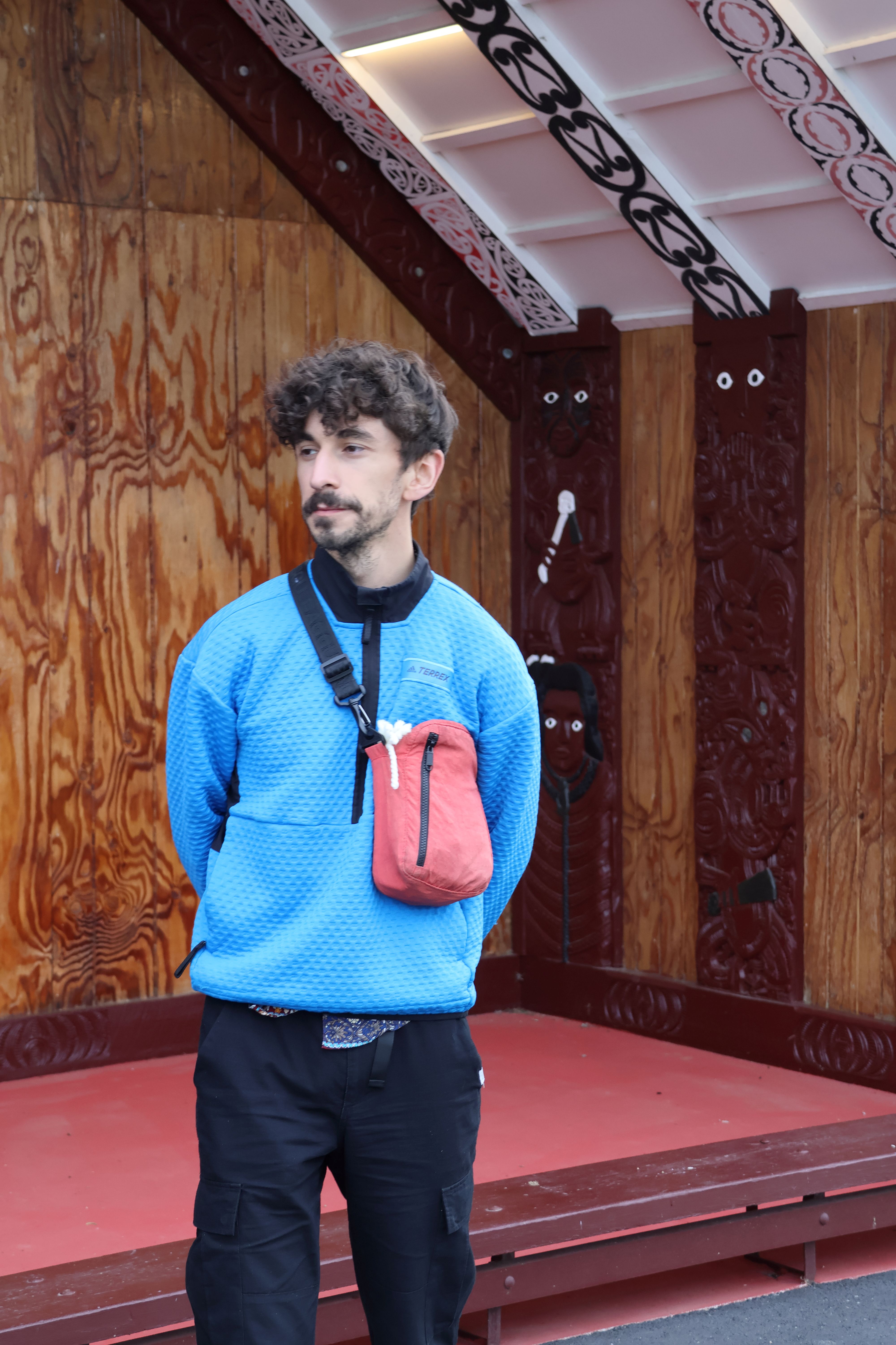 A person in a blue jacket looks off to something to the right of them.