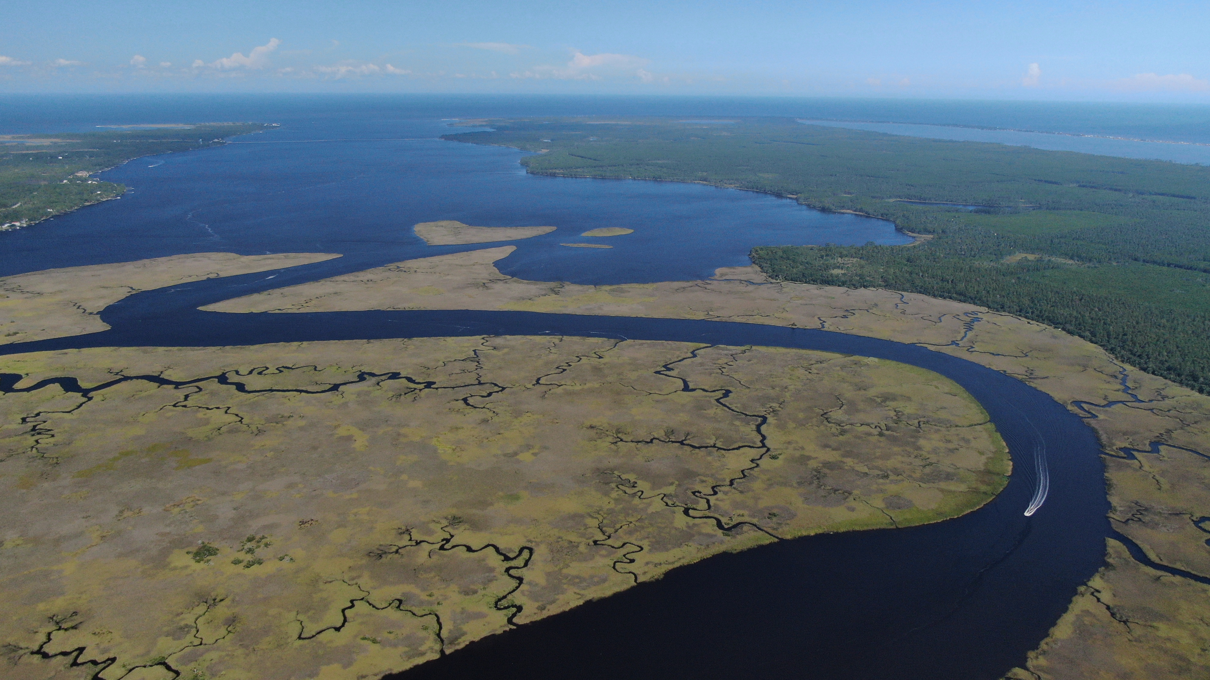 Aerial image of a marsh with a winding river connecting the fresh and salt water.