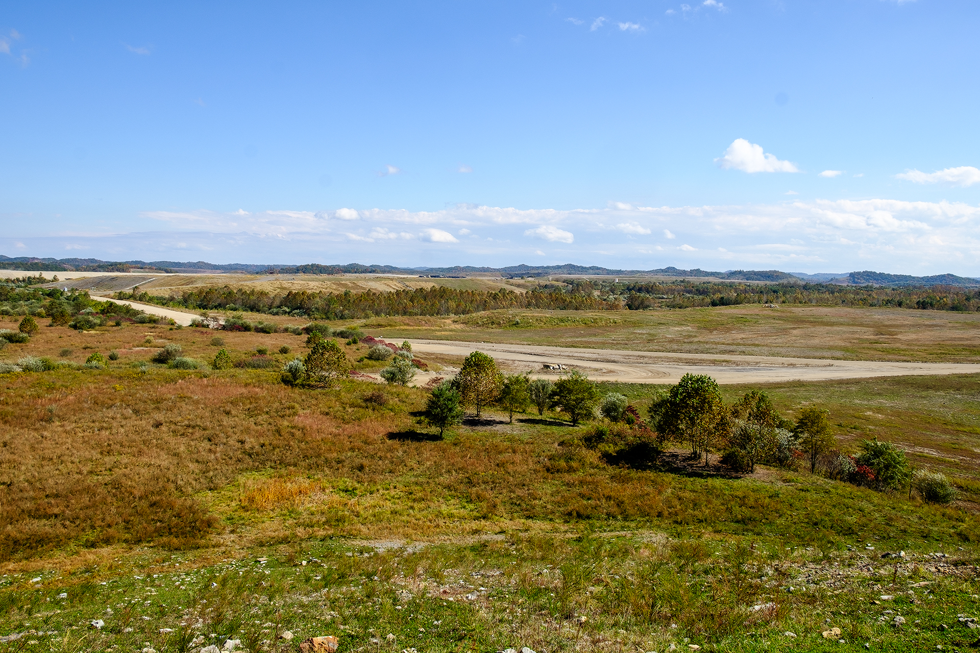 landscape with dirt road, trees and mine in distance.
