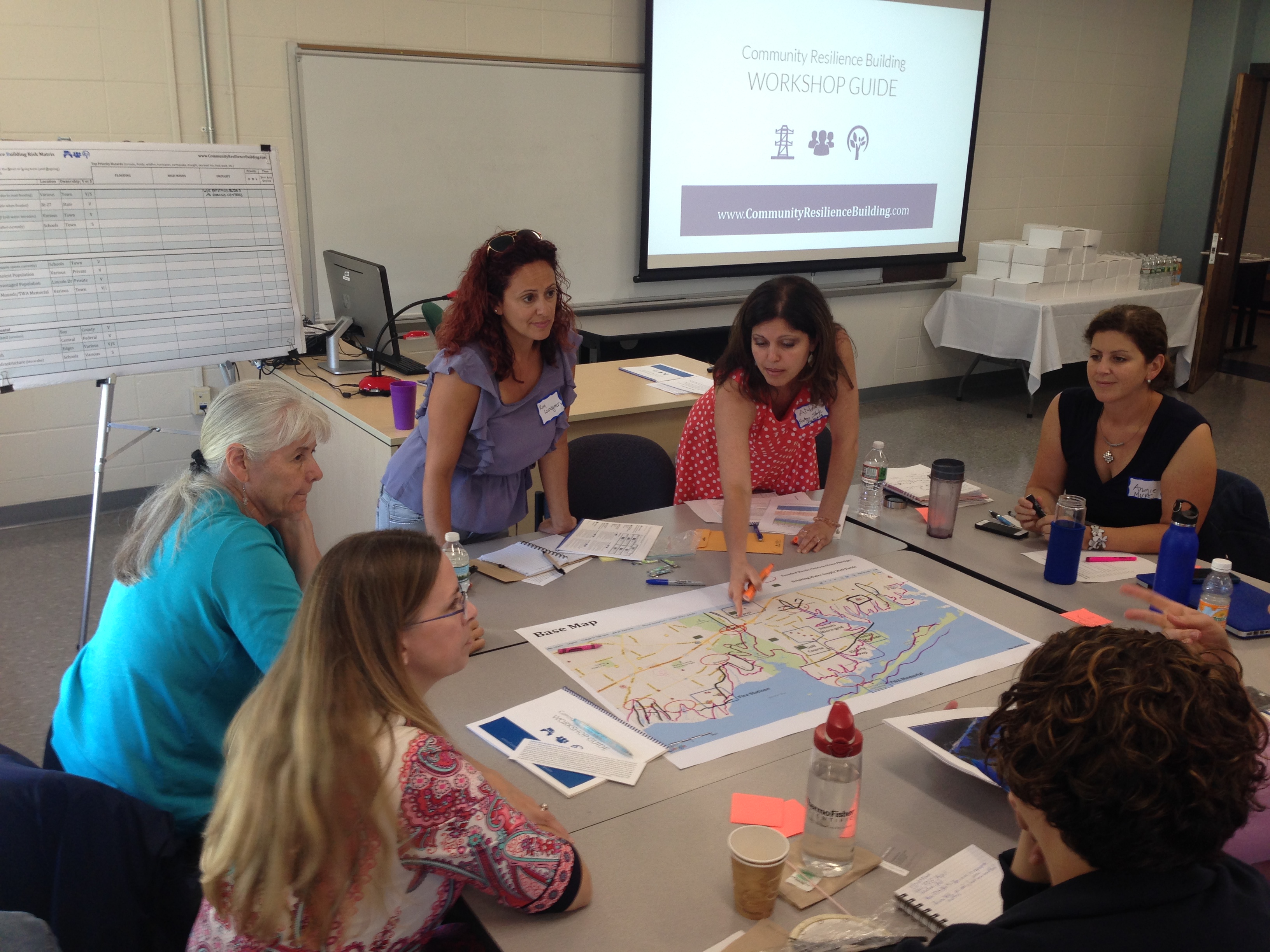 Several women gather around an indoor table.
