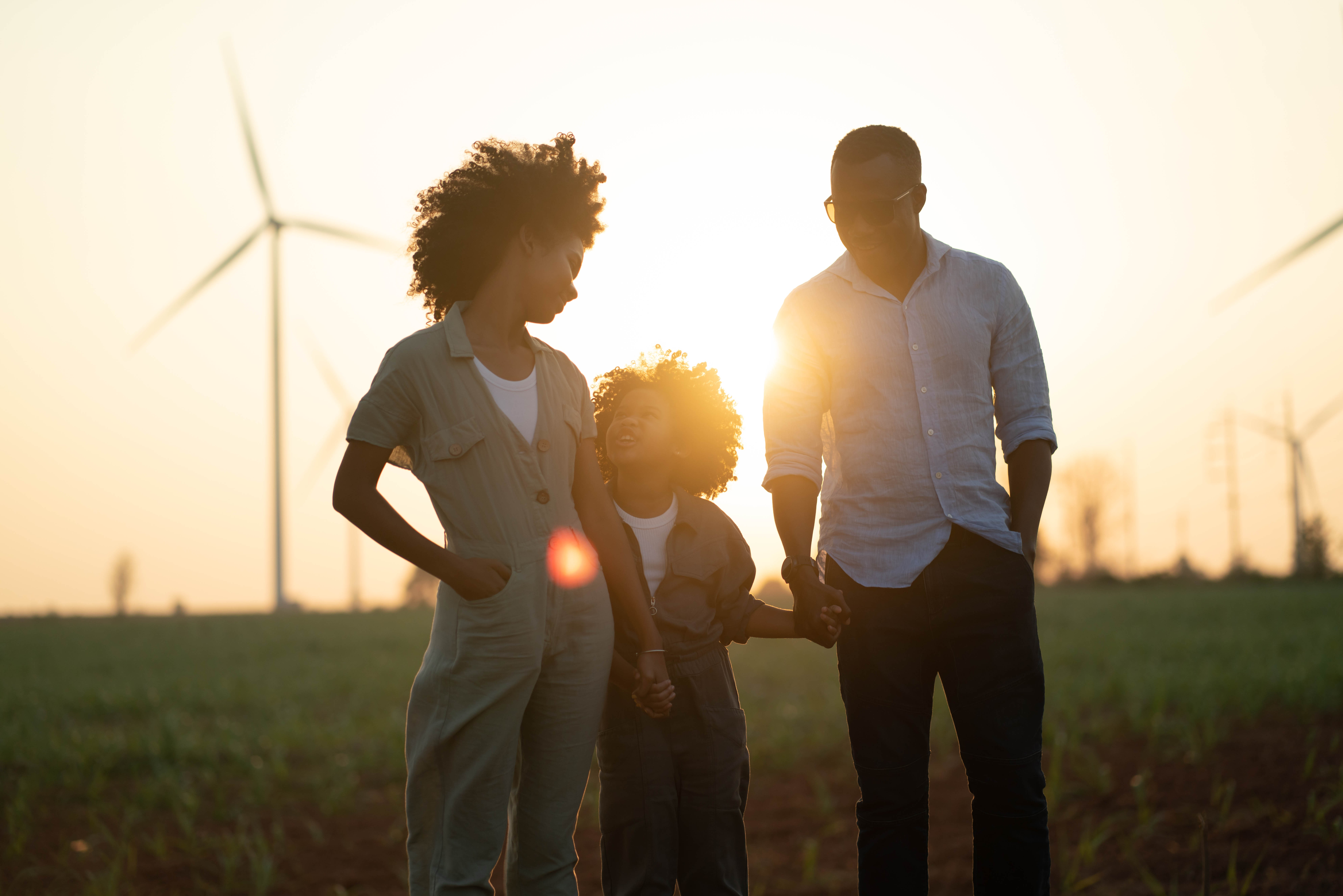 parents and young child with wind turbines in background