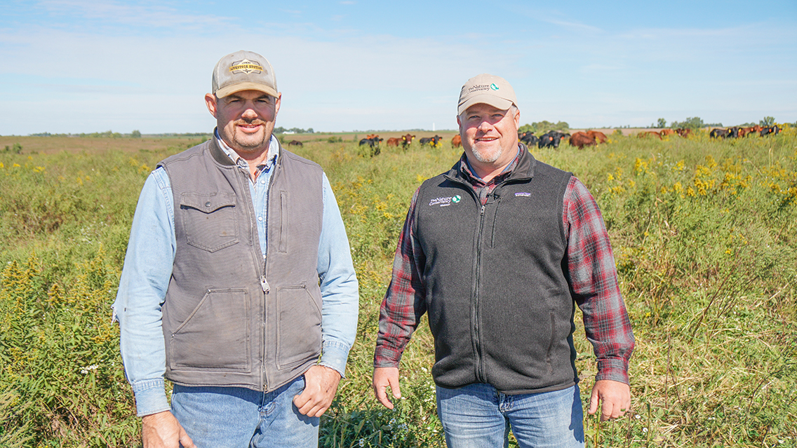 Two men outside pose for a photo.