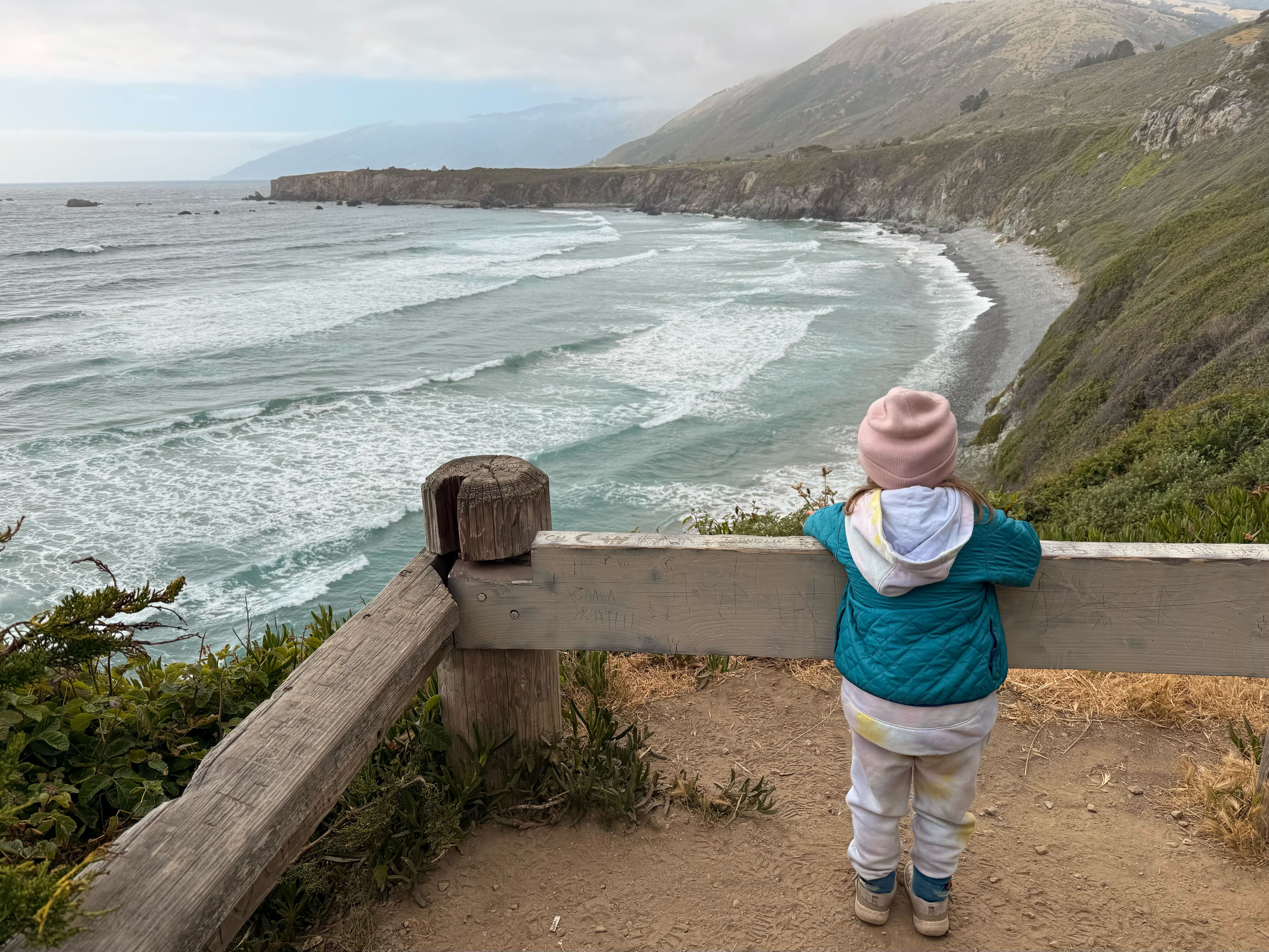 A small child looks out at the ocean. 