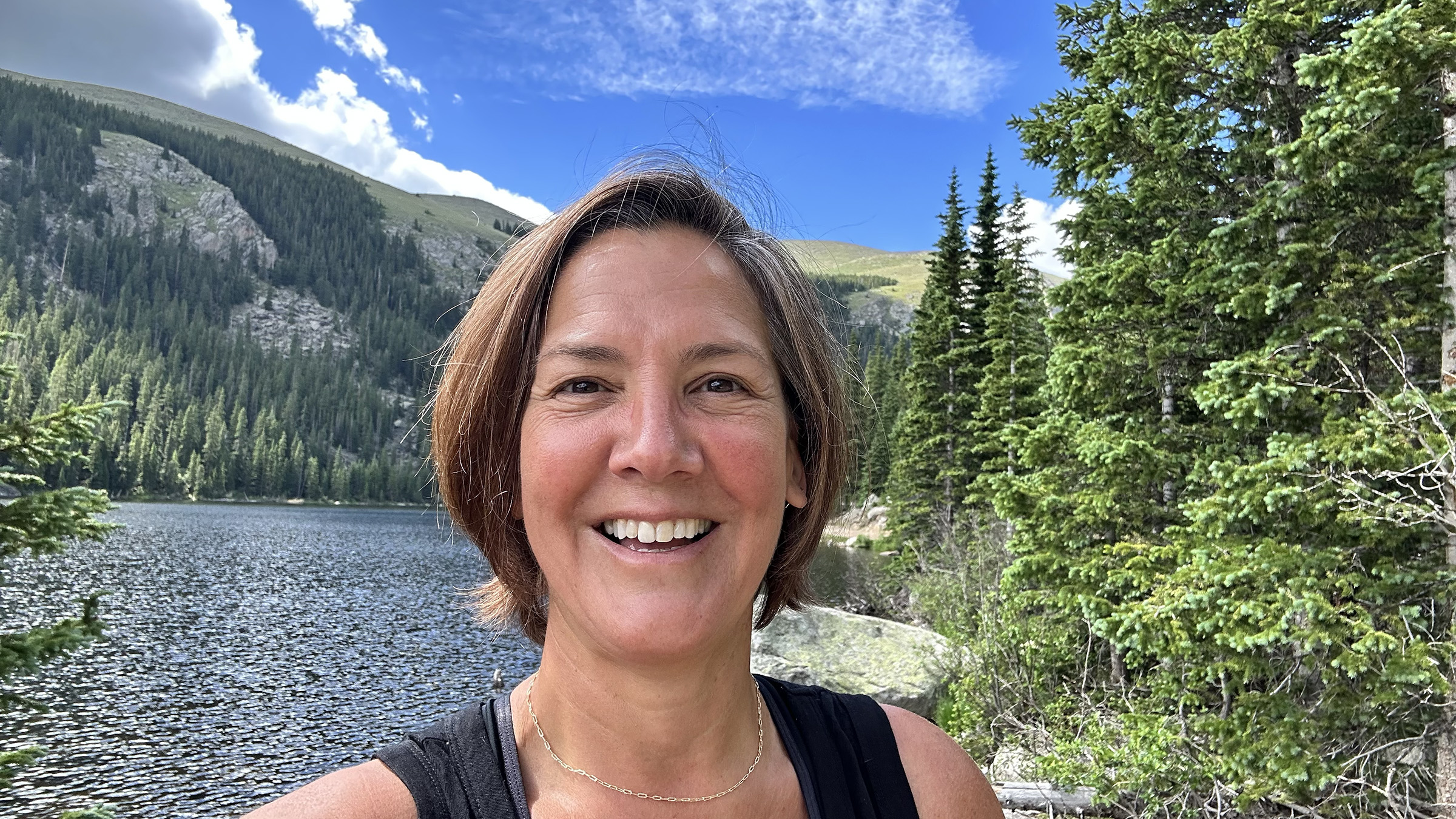 Headshot of Kris Sarri with a mountain and forest scene in background.