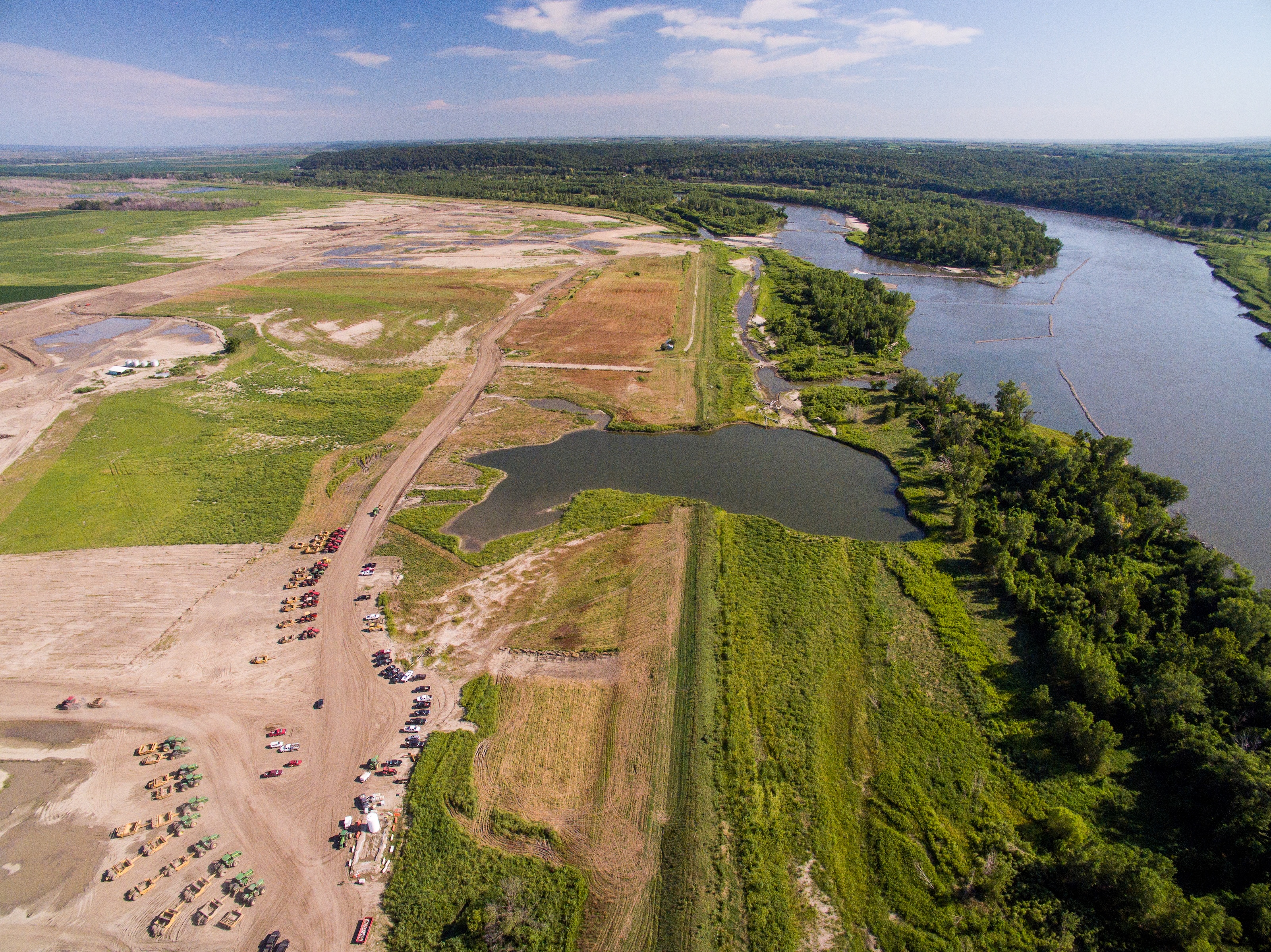 Aerial view of land between a river and levee.