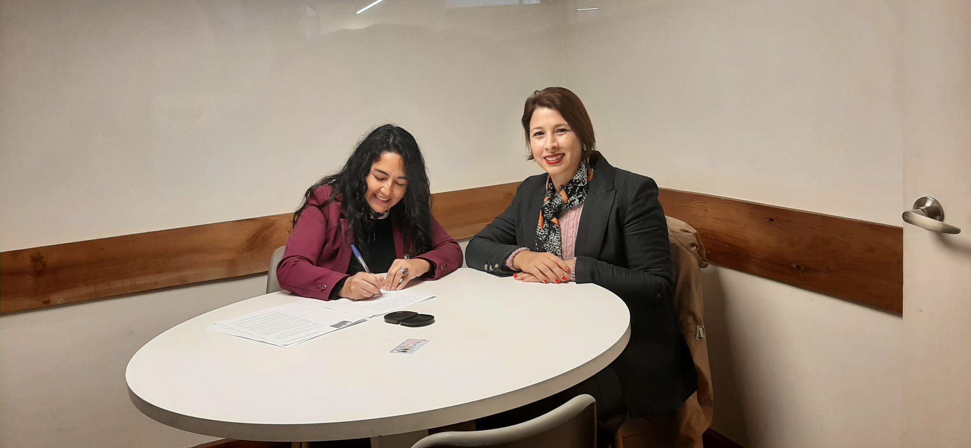 Dos personas sentadas en la firma de donación. 