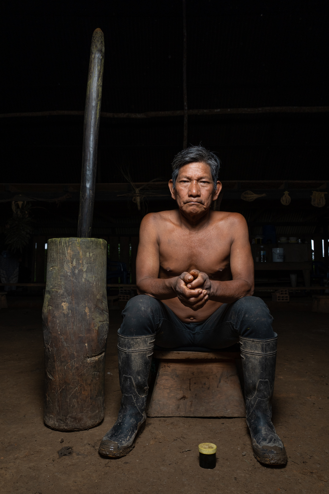 Un hombre sentado en un banco, sosteniendo un hacha grande, con una expresión concentrada en su rostro.