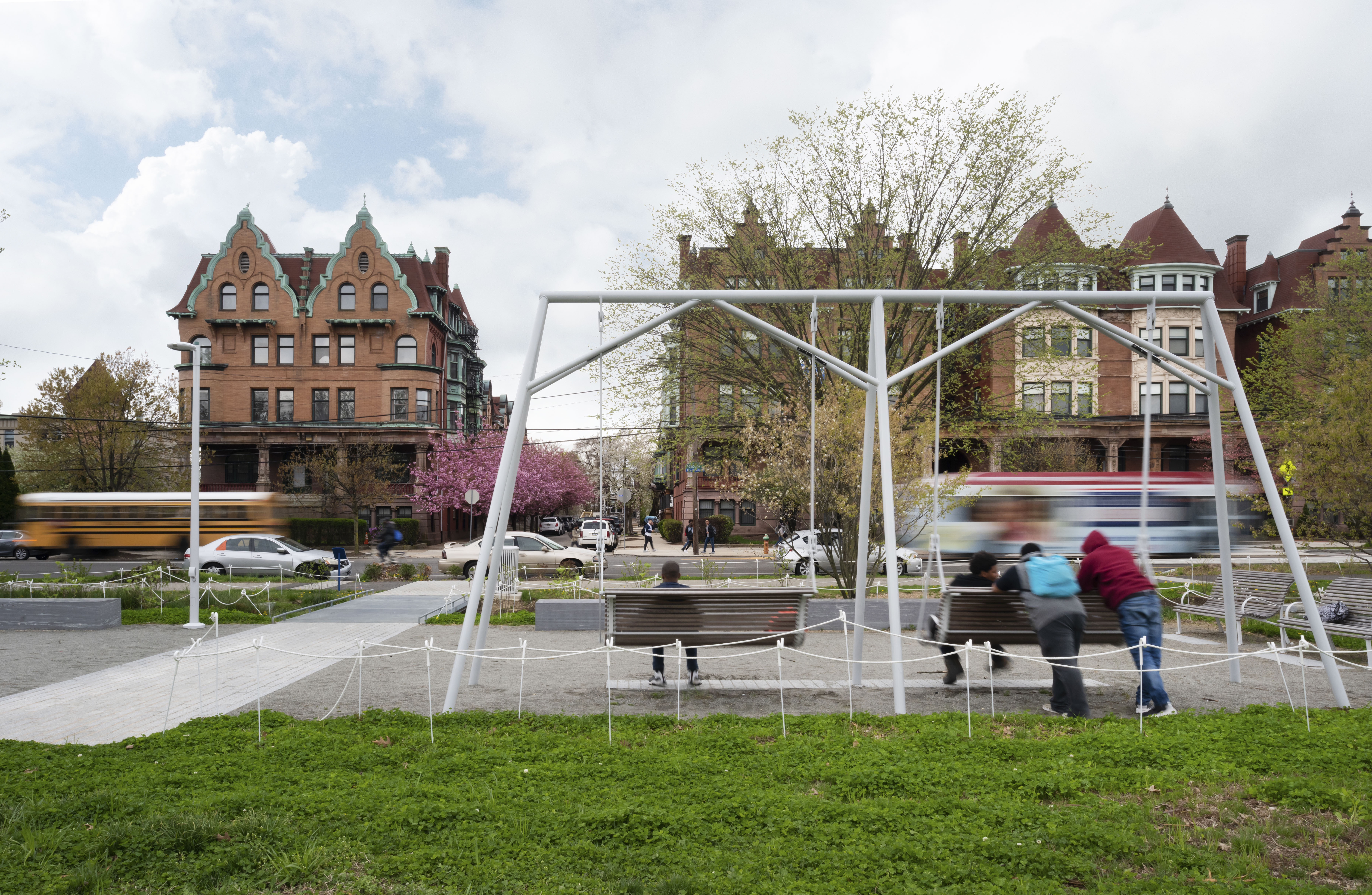 A view of a swing set on a grassy patch in a city.