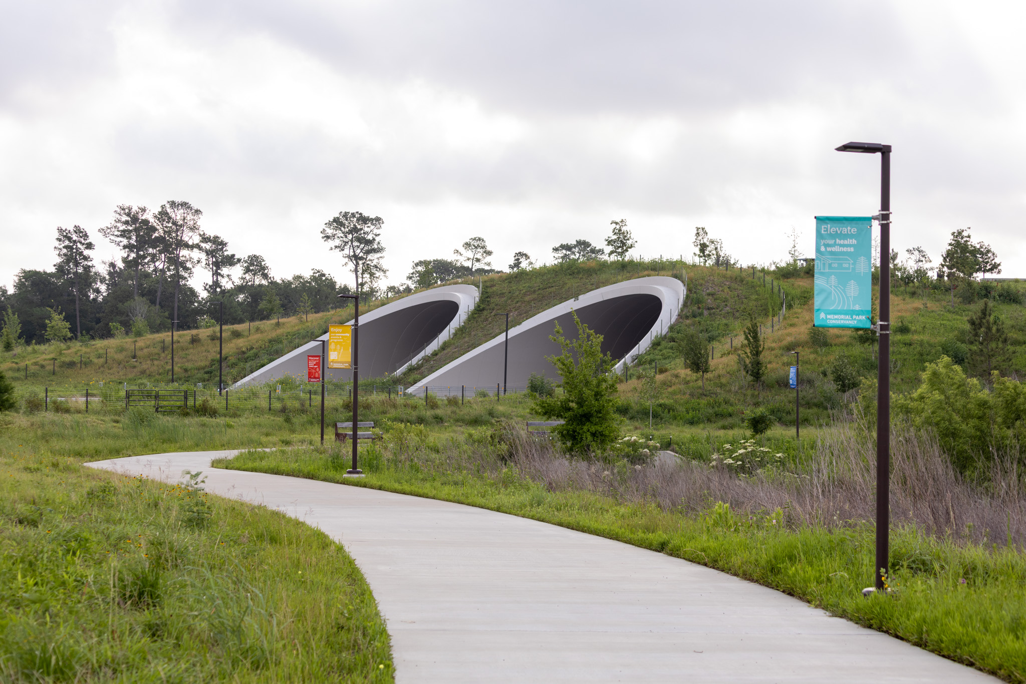 A walking trail winds through prairie near an overpass.