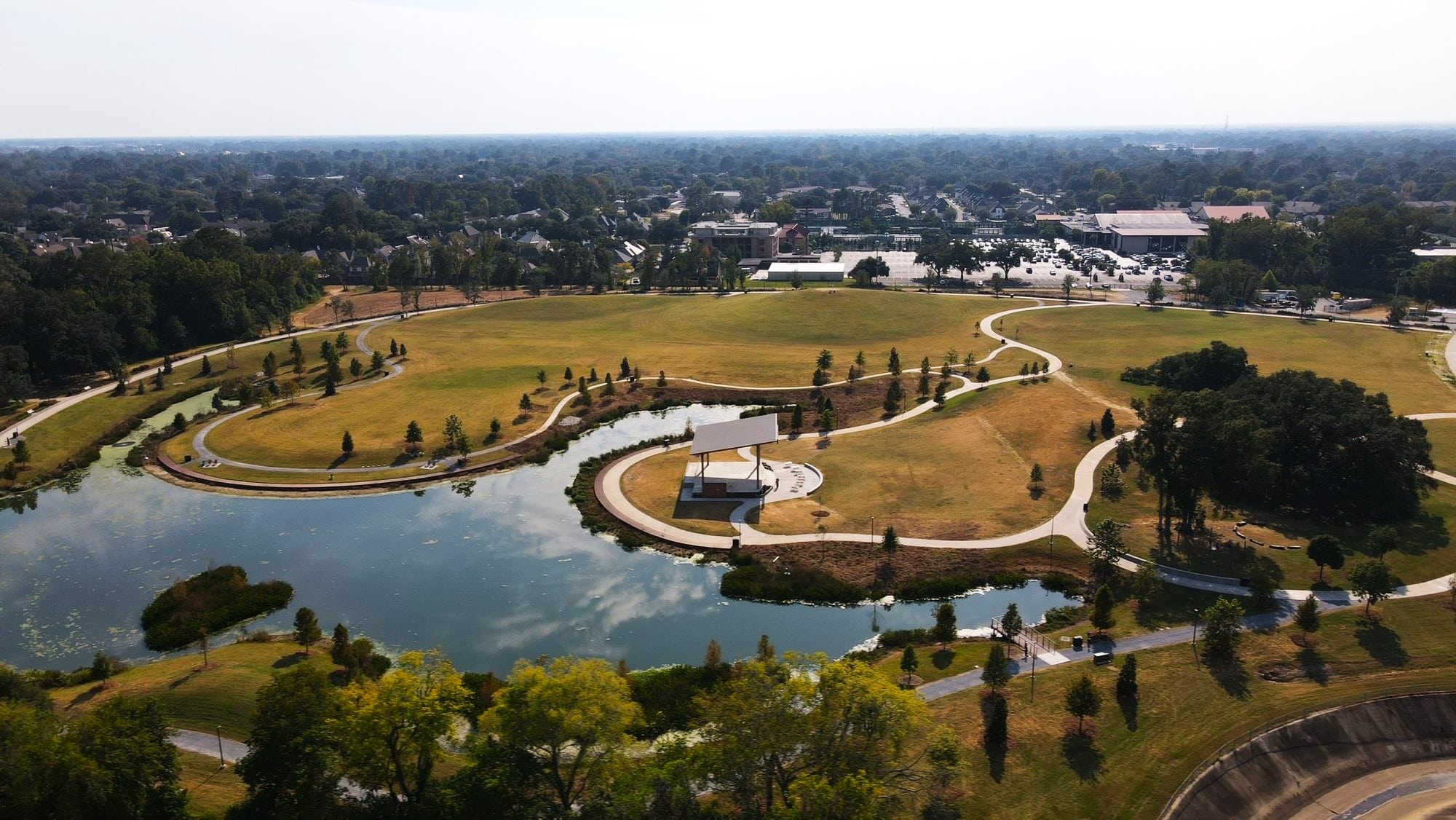 Aerial view of a small lake that surrounds a park.