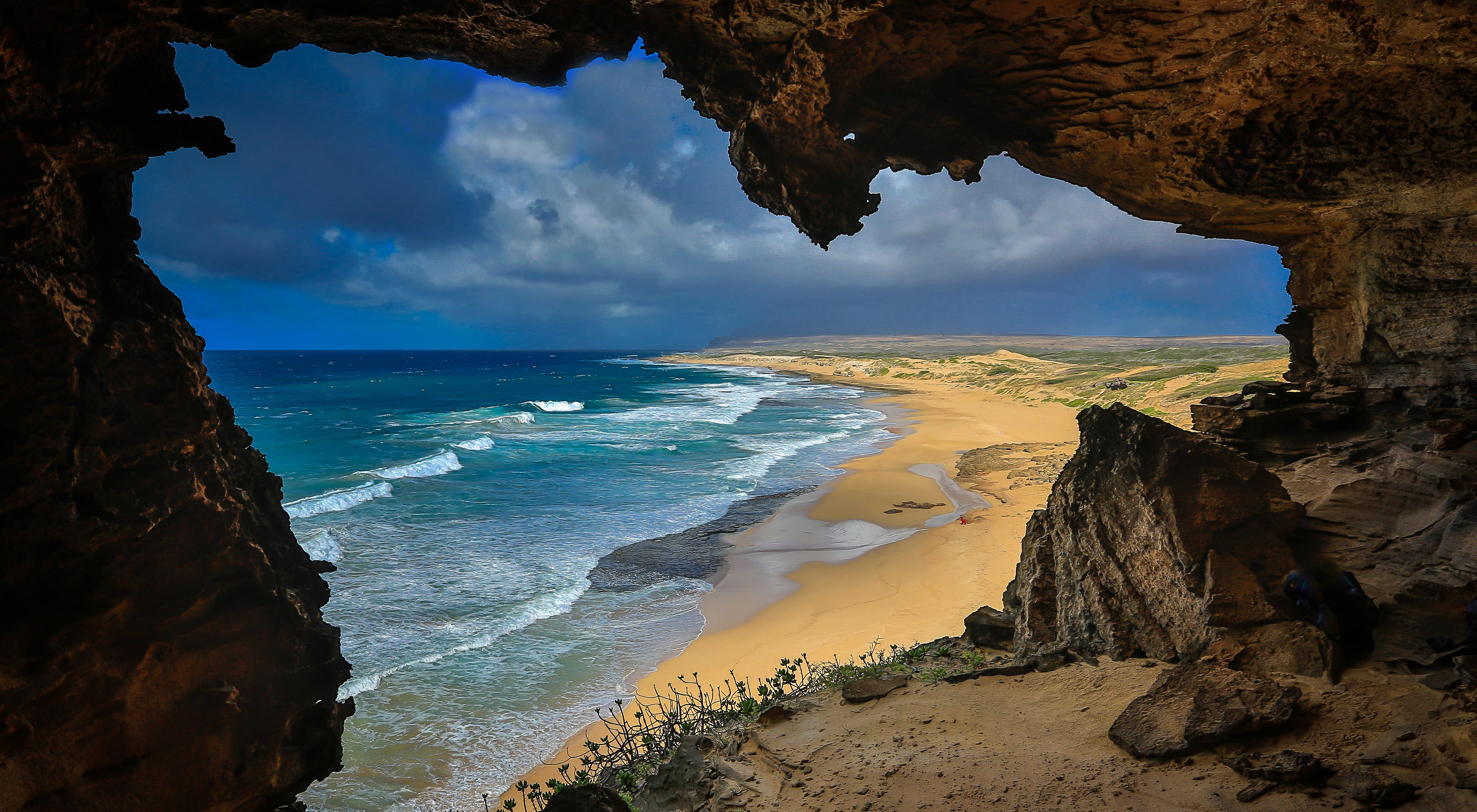 Looking out of a cave to a yellow sand beach in Hawaii. 