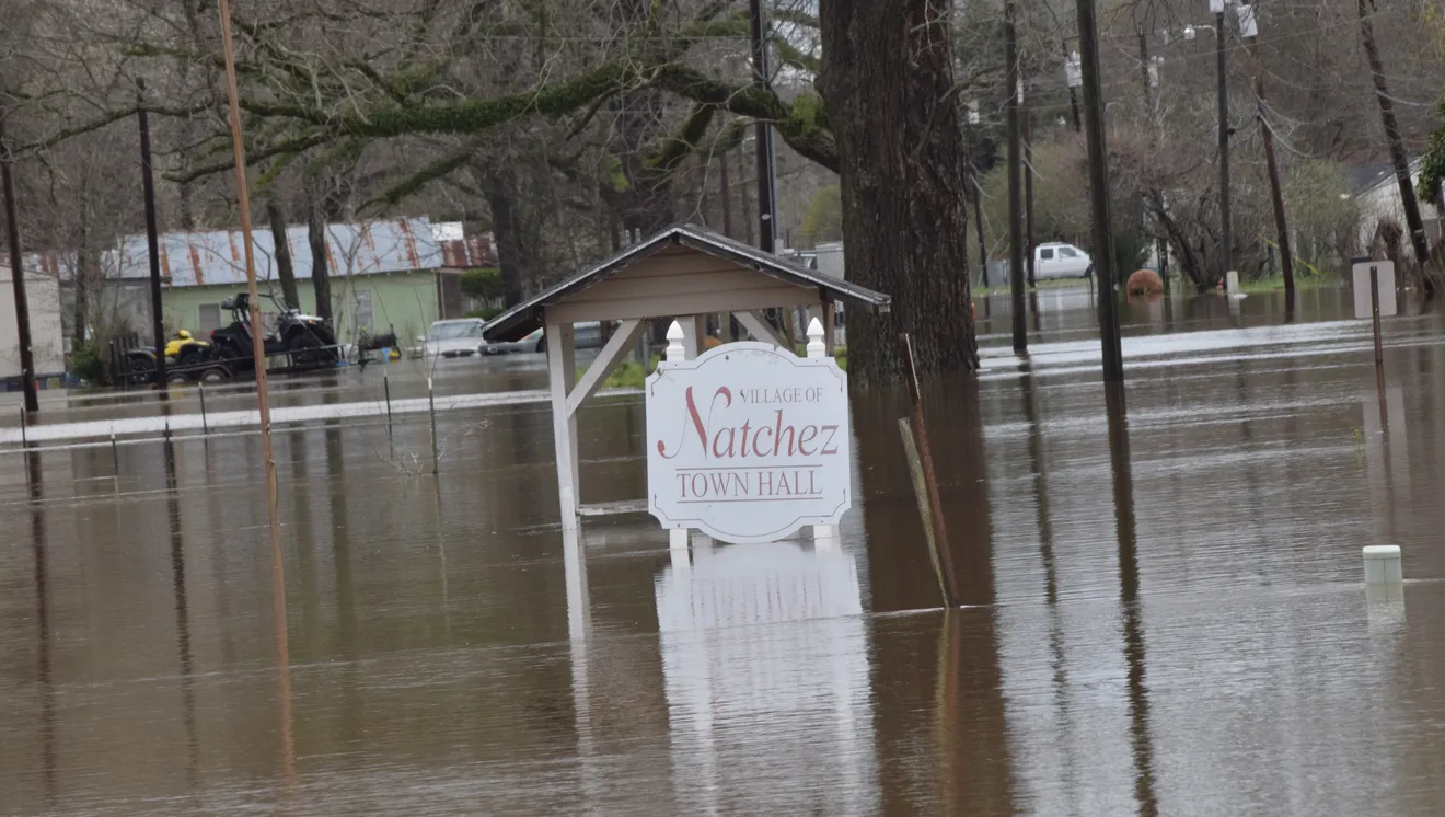 Floodwaters surround a town's sign.