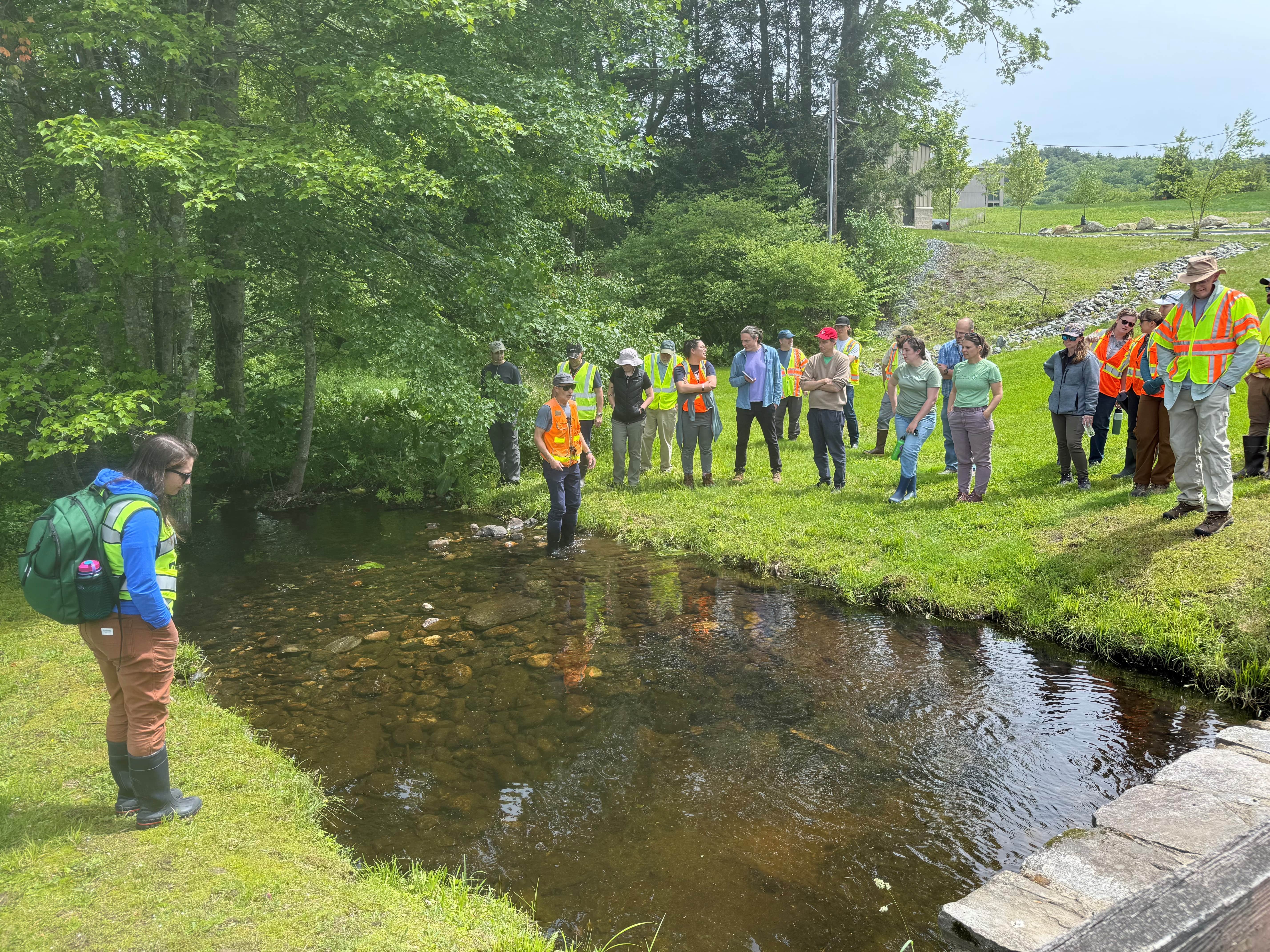 A group of people gather around a narrow waterway.