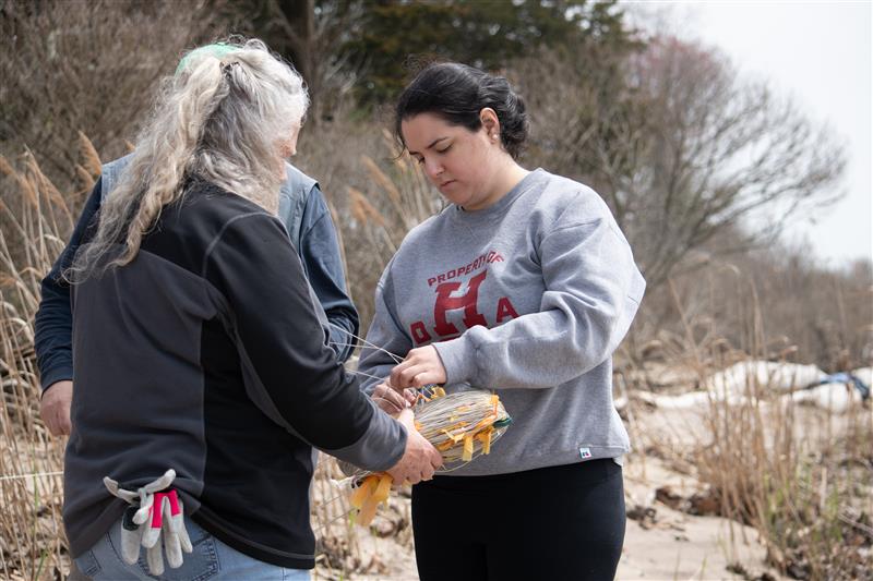 Two women look down at string held between their hands.