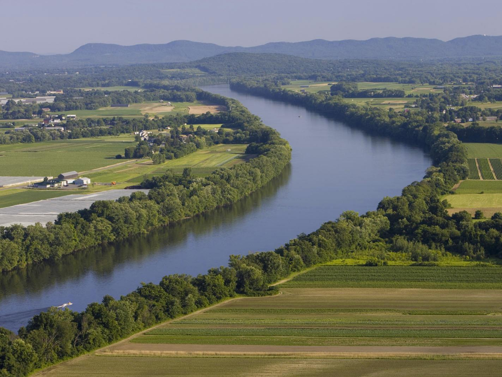A calm river winds through fields and forest.