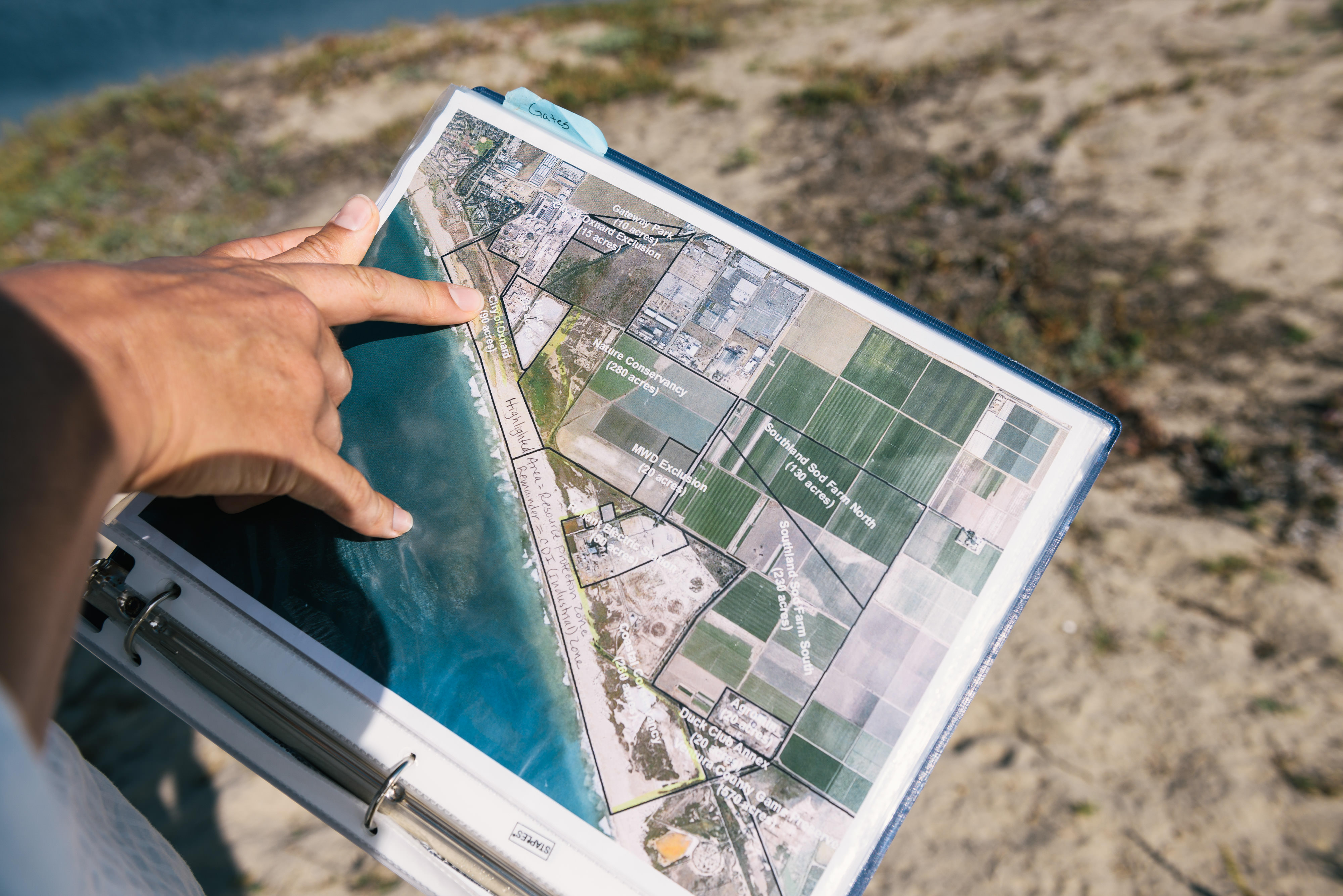 An image of a map with a person pointing out a location. 