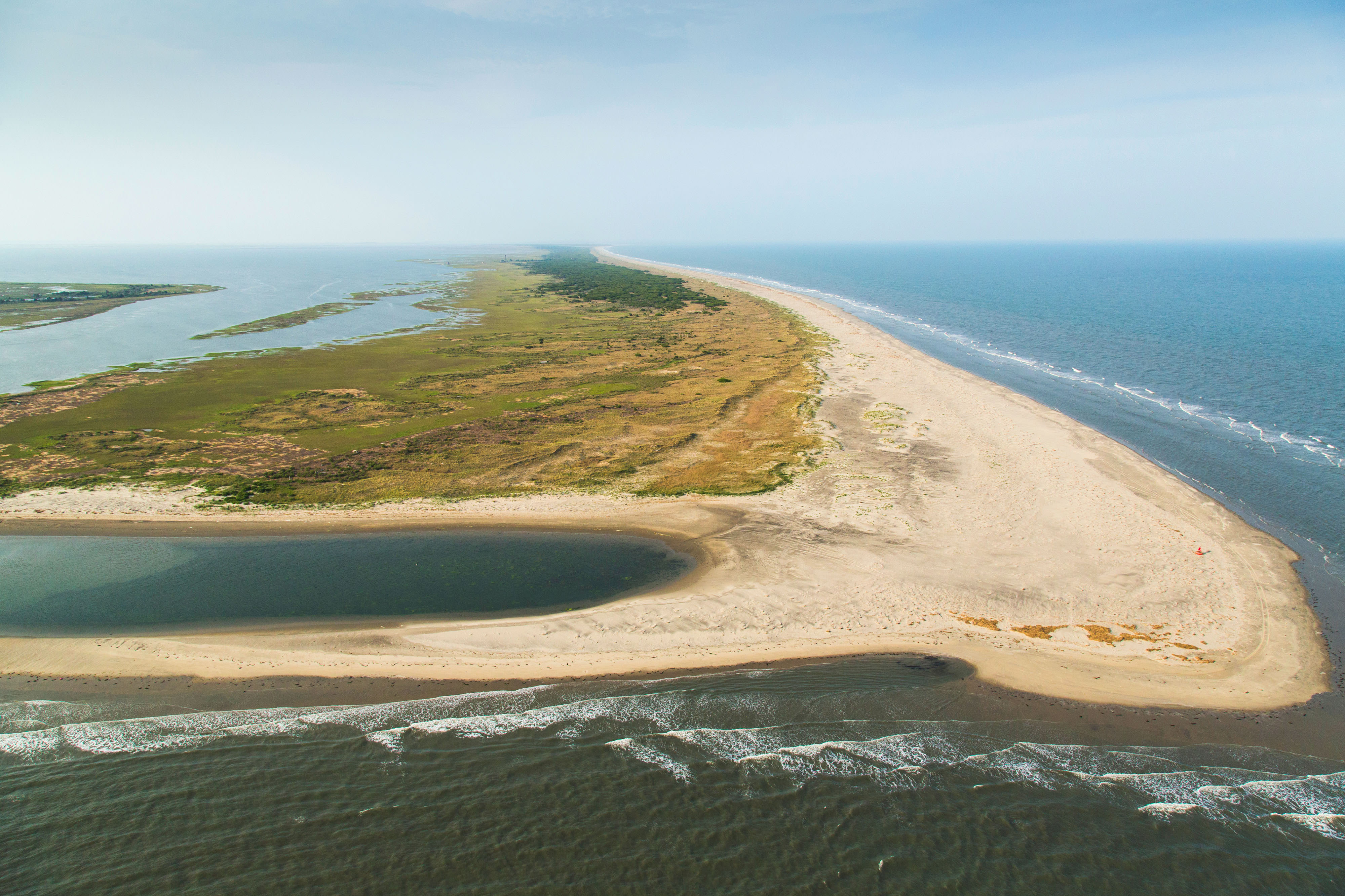 A sandy barrier island with grass extends into the water on the Eastern Shore of Virginia.