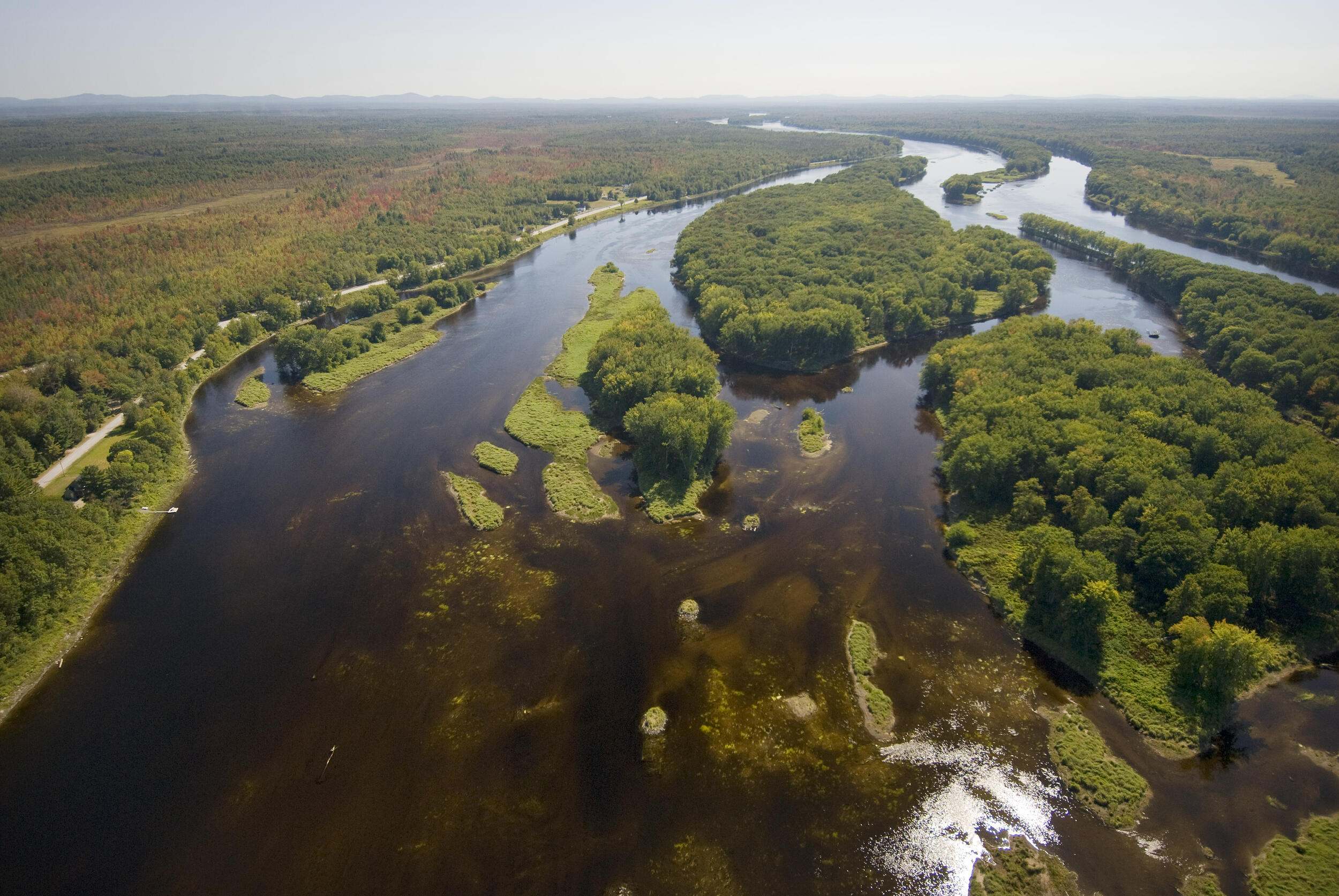 Aerial image of a river with forested islands surrounded by forests.